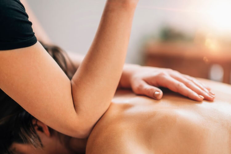 Close up of two hands massaging a person’s upper back